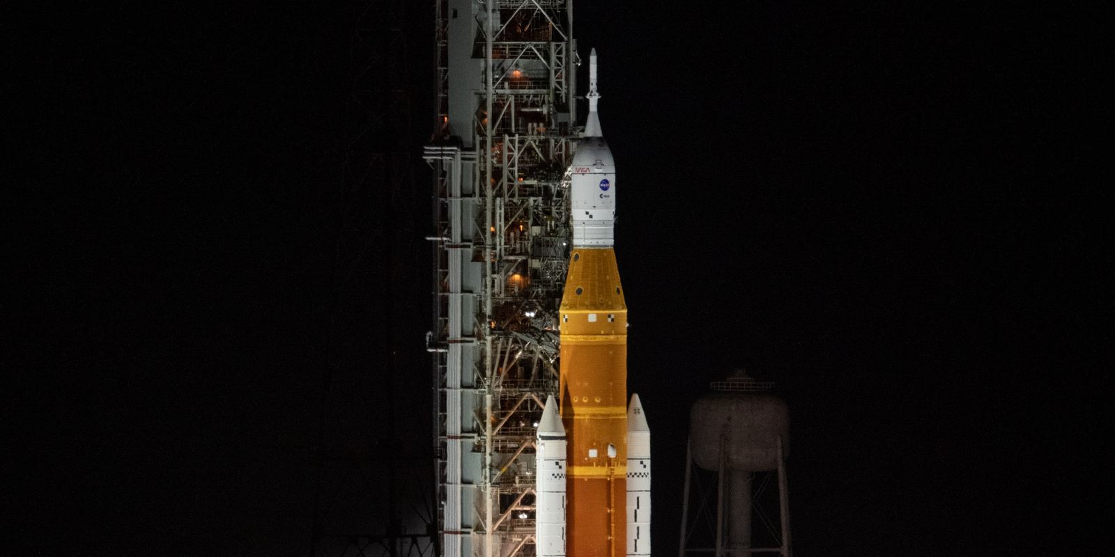 The SLS rocket launching Artemis I at night with a bright flame