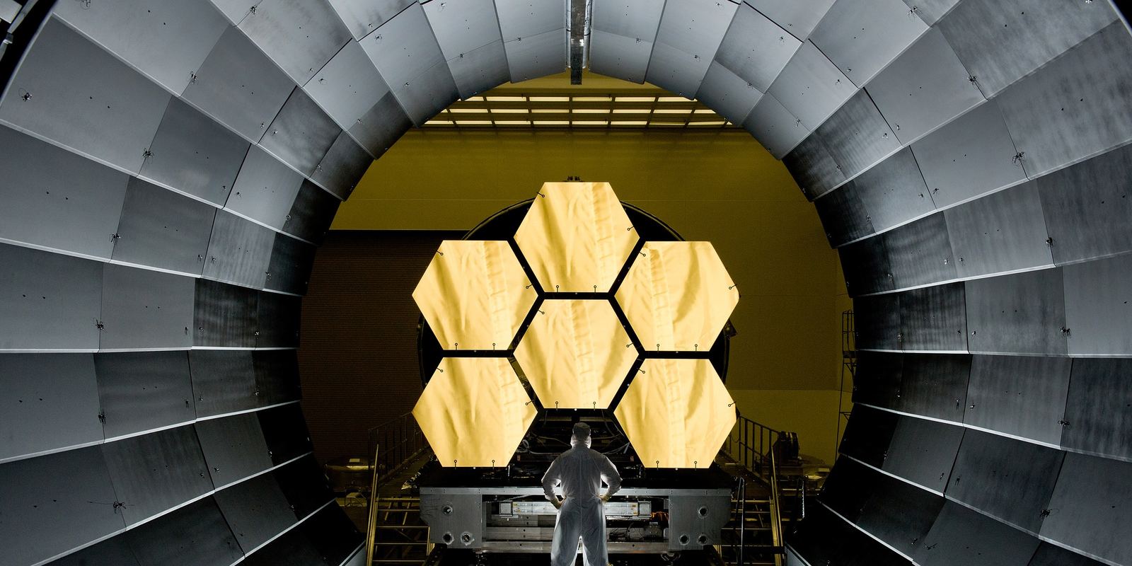 Engineers in clean-room suits in front of Webb's gold hexagonal mirror