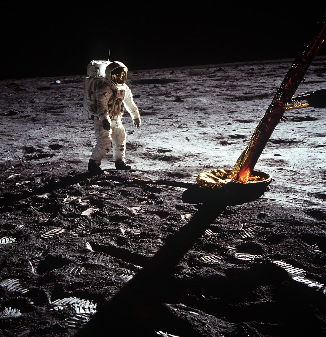 Astronaut Buzz Aldrin in a white spacesuit walking near a leg of the Apollo 11 lunar module