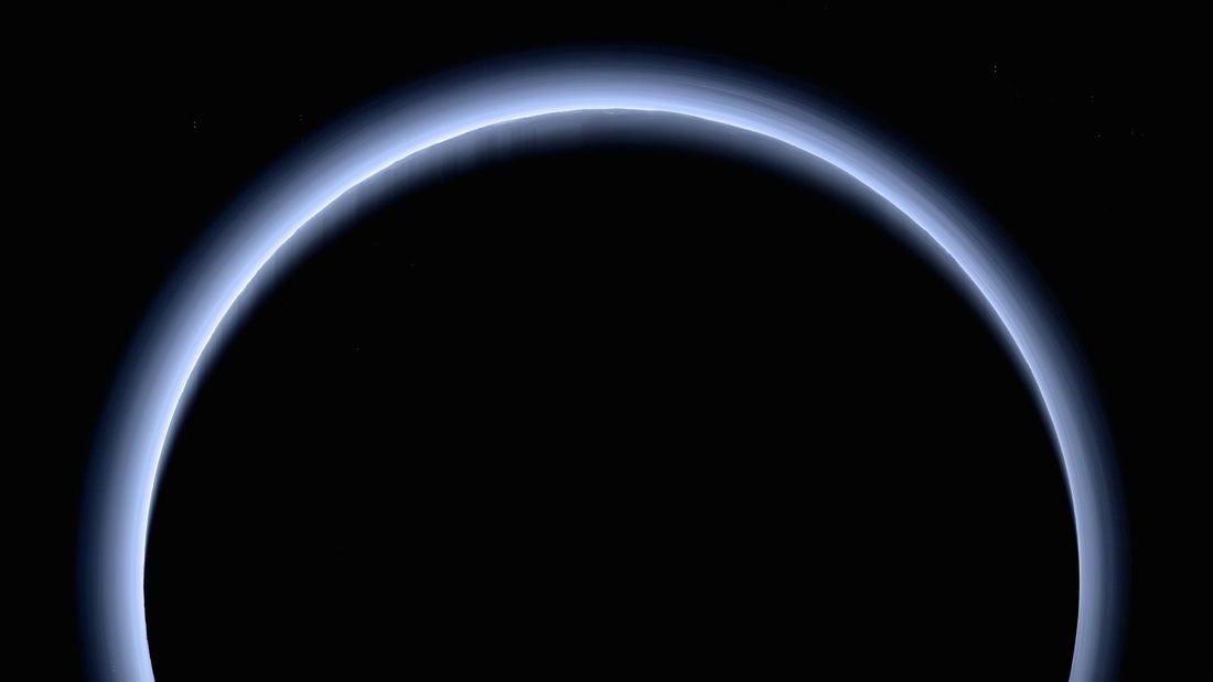 A thin crescent of Pluto backlit by the Sun, ringed by glowing blue layers of haze