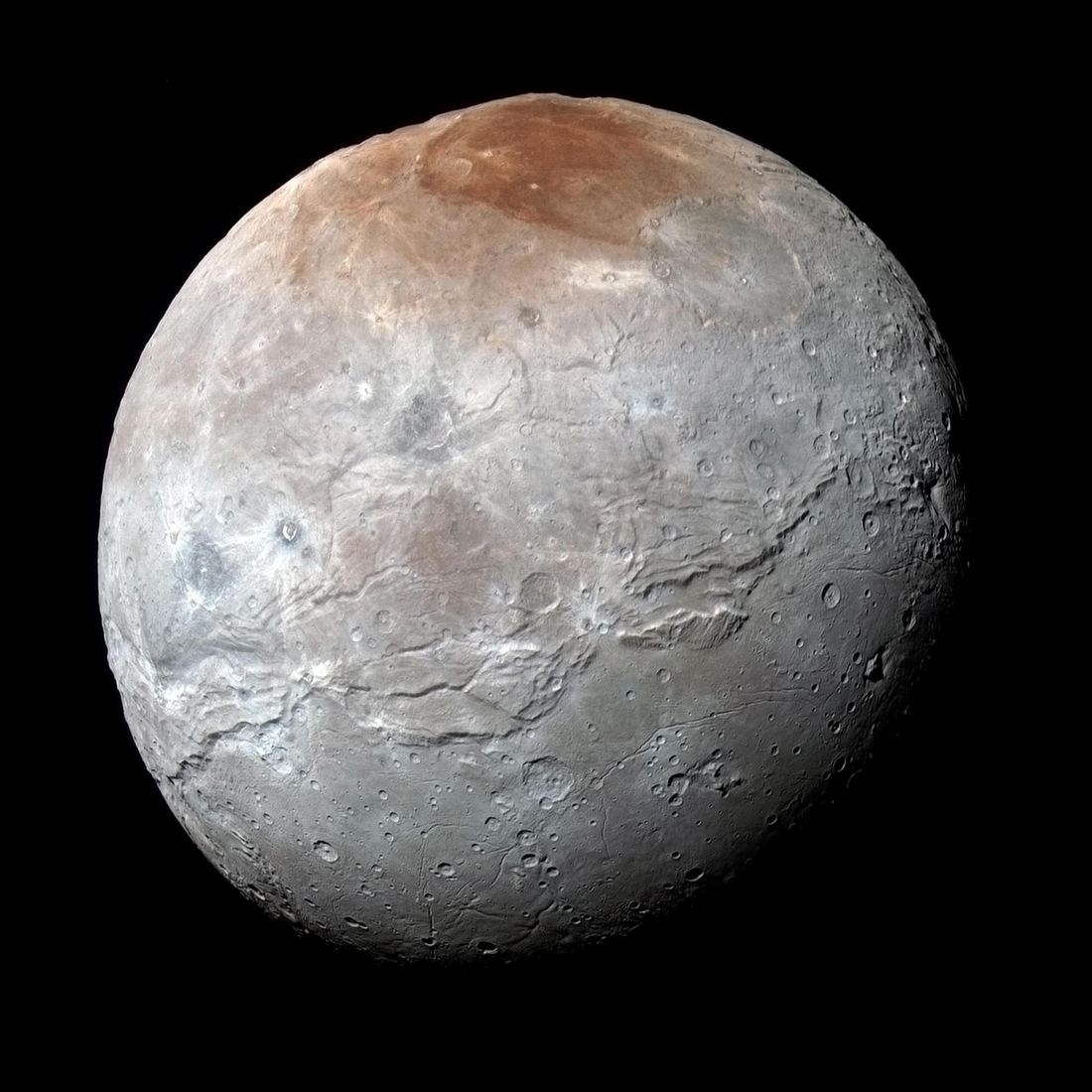 Pluto's largest moon Charon in enhanced color, gray with a dark reddish polar cap