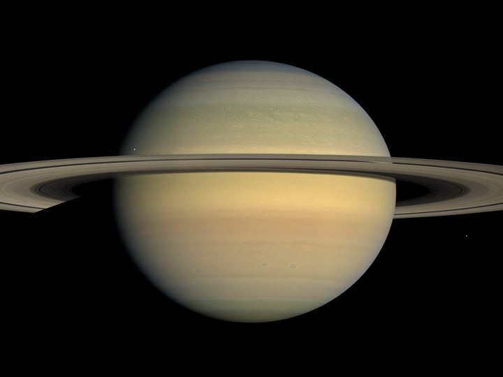Saturn with its broad, thin rings seen nearly edge-on from Cassini, casting a narrow shadow across the planet
