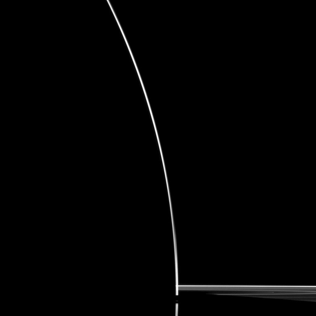 A dark silhouette of Saturn ringed by sunlit rings, seen from the planet's night side