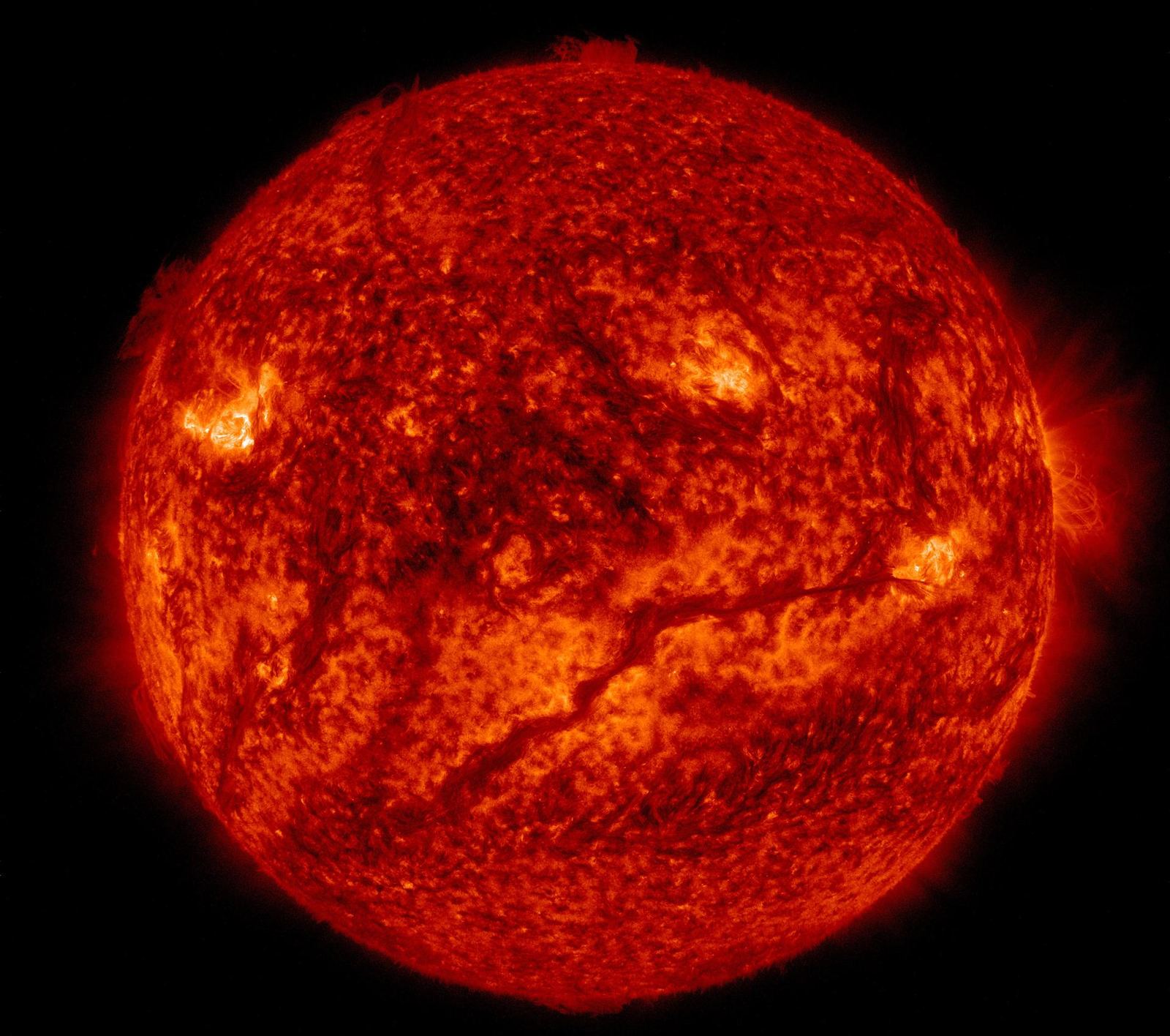 The Sun in extreme ultraviolet light, glowing gold with a long dark filament snaking across its lower half